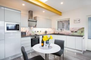 a kitchen with white cabinets and a table with yellow flowers at Three Lochs View, Ardelve, by Dornie in Dornie