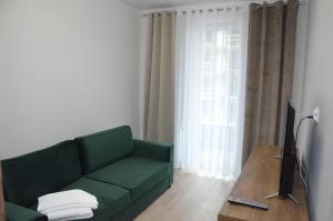 a living room with a green couch and a television at Apartament Luna Baltic Marina Residence in Kołobrzeg