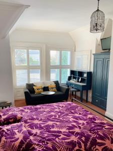 a bedroom with a purple bed and a couch at Derrin Guest House in Larne