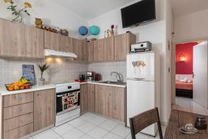 a kitchen with wooden cabinets and a white refrigerator at Blossom in Ierapetra +14 photos