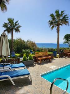 una piscina con sillas, mesas y palmeras en Kanalli Apartments, en Pomos