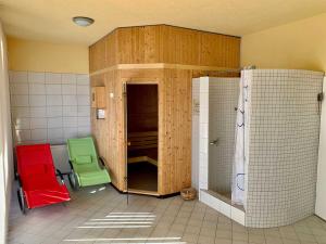 a bathroom with a shower and two green chairs at Ferienwohnung mit Meerblick und Sauna in Göhren