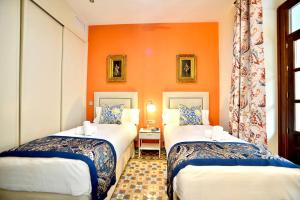 Duas camas num quarto com uma parede laranja em Classic and Luxury- 2Bd 2Bth- Sierpes em Sevilha