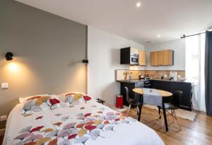 a bedroom with a bed and a table and a kitchen at Maloca' Joffre in La Roche-sur-Yon