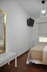 1 dormitorio con cama, espejo y TV en Alojamiento Santa Maria II en Milladoiro