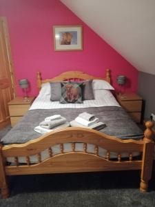 a bedroom with a wooden bed with pink walls at Corrie View in Invergarry