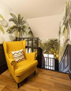 a yellow chair sitting on a balcony with palm wallpaper at Maloca' Joffre in La Roche-sur-Yon