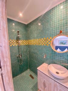 baño de azulejos verdes con ducha y lavamanos en Riad Al Madina, en Essaouira