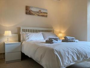 Un dormitorio con una cama con sábanas blancas y dos lámparas. en Great location, quiet yet 5 mins to Bowness centre with walks from the door and parking, en Bowness-on-Windermere