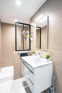uma casa de banho com um lavatório branco e um espelho. em Appartement POP au coeur du centre ville em Mâcon