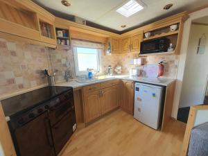 a kitchen with wooden cabinets and a sink and a dishwasher at The Topaz Caravan HF12 in Ingoldmells
