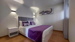 ザンブジェイラ・ド・マールにあるRosa dos Ventosのベッドルーム1室(紫のシーツと紫の毛布を使用したベッド1台付)