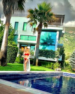 a woman in a dress standing next to a swimming pool at Beach Hiking Holiday Villa Luanit in Tragjas