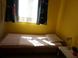 Cama en habitación amarilla con ventana en Ecer Pansiyon, en Kusadasi