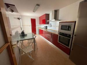 uma cozinha com armários vermelhos, uma mesa e um micro-ondas em Casa Moraira em Águilas