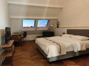a bedroom with a bed and a desk and two windows at Zennon in Geraardsbergen