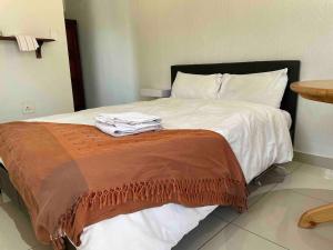 een bed met witte lakens en een bruine deken bij Private and cozy in Sandton