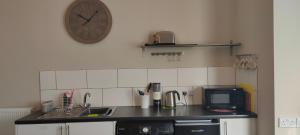 a kitchen with a counter and a clock on the wall at Fishtail House - Stylish Apartments minutes from the sea in Hornsea