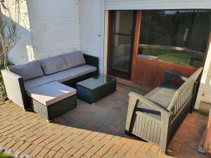 a patio with a couch and a chair next to a door at 37m² 1,5 Zimmer mit Terrasse und super Badezimmer in Tangstedt