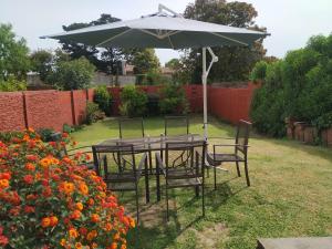 Una mesa y sillas bajo una sombrilla en un jardín. en Chalet en Punta Mogotes - Sólo Familias - NO se aceptan grupos de jóvenes, en Mar del Plata