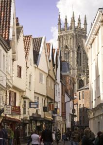 Un groupe de personnes marchant dans une rue avec une cathédrale dans l'établissement 50a Low Petergate, à York