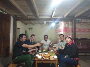 een groep mensen die rond een tafel eten bij Ly Thi Chuong Homestay in Quản Bạ