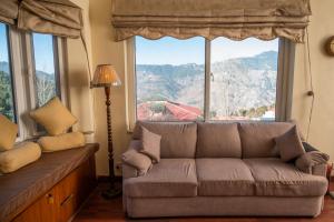 a living room with a couch and large windows at Sarah's Lodge in Murree