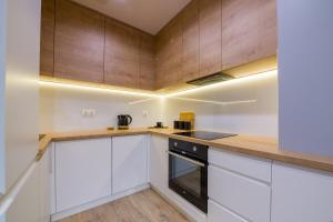 uma cozinha com armários brancos e paredes de madeira em Apartament przy Fabrycznym em Lódź