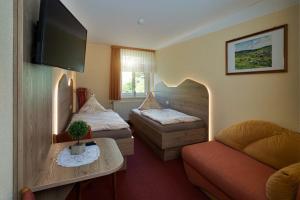 a hotel room with two beds and a couch at Landgasthof Zum Schützenhaus Sosa in Eibenstock