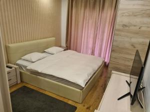 ein kleines Schlafzimmer mit einem Bett mit weißer Bettwäsche in der Unterkunft COSMOPOLIS in Ştefăneştii de Jos