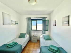 two twin beds in a room with a window at Maresía Apartamento in El Golfo