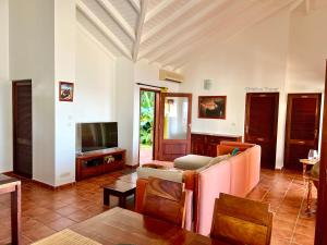 a living room with a couch and a tv at Villa Le Refuge du Pirate in Deshaies