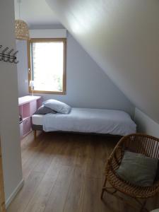 a bedroom with a bed and a chair and a window at La petite brise in Plouër-sur-Rance