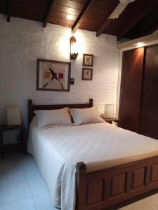 1 dormitorio con 1 cama grande con sábanas blancas en Complejo Casa Clara en Santa Clara del Mar