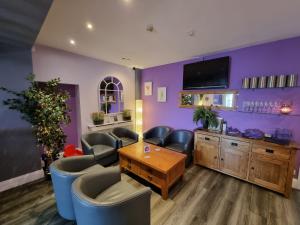 a waiting room with purple walls and chairs and a table at The Dolphin Hotel in Pembroke Dock