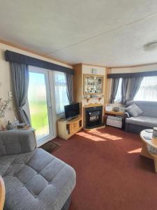 a living room with a couch and a tv at The Topaz Caravan HF12 in Ingoldmells