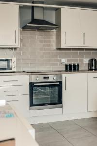 a kitchen with white cabinets and an oven at Dealhouse-Apartments 5 in Huddersfield