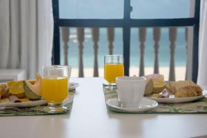 una mesa con dos platos de comida y dos vasos de zumo de naranja en Classic Flat Residence Service ap.902, en Fortaleza