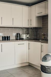 Biała kuchnia z białymi szafkami i urządzeniami w obiekcie Dealhouse-Apartments 5 w mieście Huddersfield