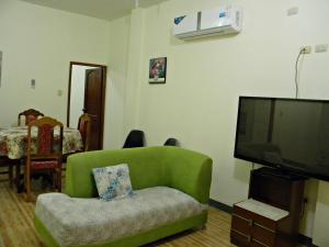 a living room with a green couch and a flat screen tv at Casa Blanca Puerto López in Puerto López