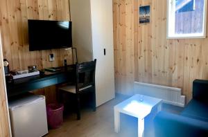 ein Wohnzimmer mit einem Schreibtisch und einem TV in der Unterkunft Sandsjögården Holiday Resort in Blattniksele