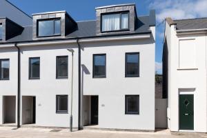 a white house with a black roof at Modern Four Bedroom Four Bathroom Home in Cheltenham