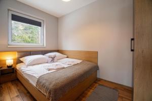 Dormitorio pequeño con cama y ventana en Osada Wróblonki - Apartamenty, en Wisła