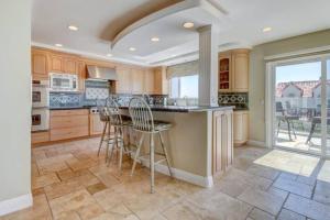 a kitchen with wooden cabinets and a island with bar stools at The Bridge At South Oceanside is the Perfect Family Beach House now with AC in Oceanside