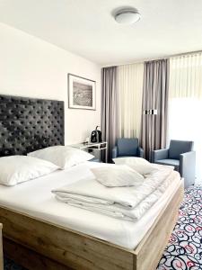 a bedroom with a large white bed and two chairs at Pfefferhöhe Hotel & Restaurant in Alsfeld