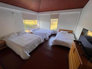 um quarto de hotel com duas camas e uma TV de tela plana em Casa Campestre Villa Luna em Sogamoso