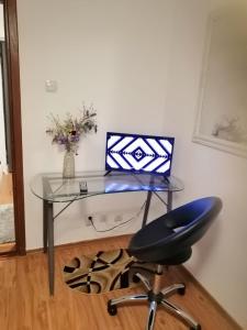 a glass desk with a laptop and a chair at Masaryss apartament Tulcea in Tulcea