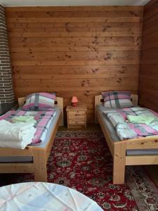 two beds in a room with wooden walls at Monteurzimmer Ahnetal Zweibettzimmer Einzelzimmer mit eigenem Bad in Dörnberg