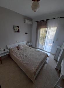 a bedroom with a bed and a large window at Doukas in Skala Rachoniou