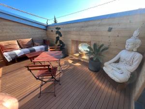 eine Terrasse mit einer Statue eines Buddha auf einem Deck in der Unterkunft Chai de Villeneuve in Villeneuve-la-Rivière